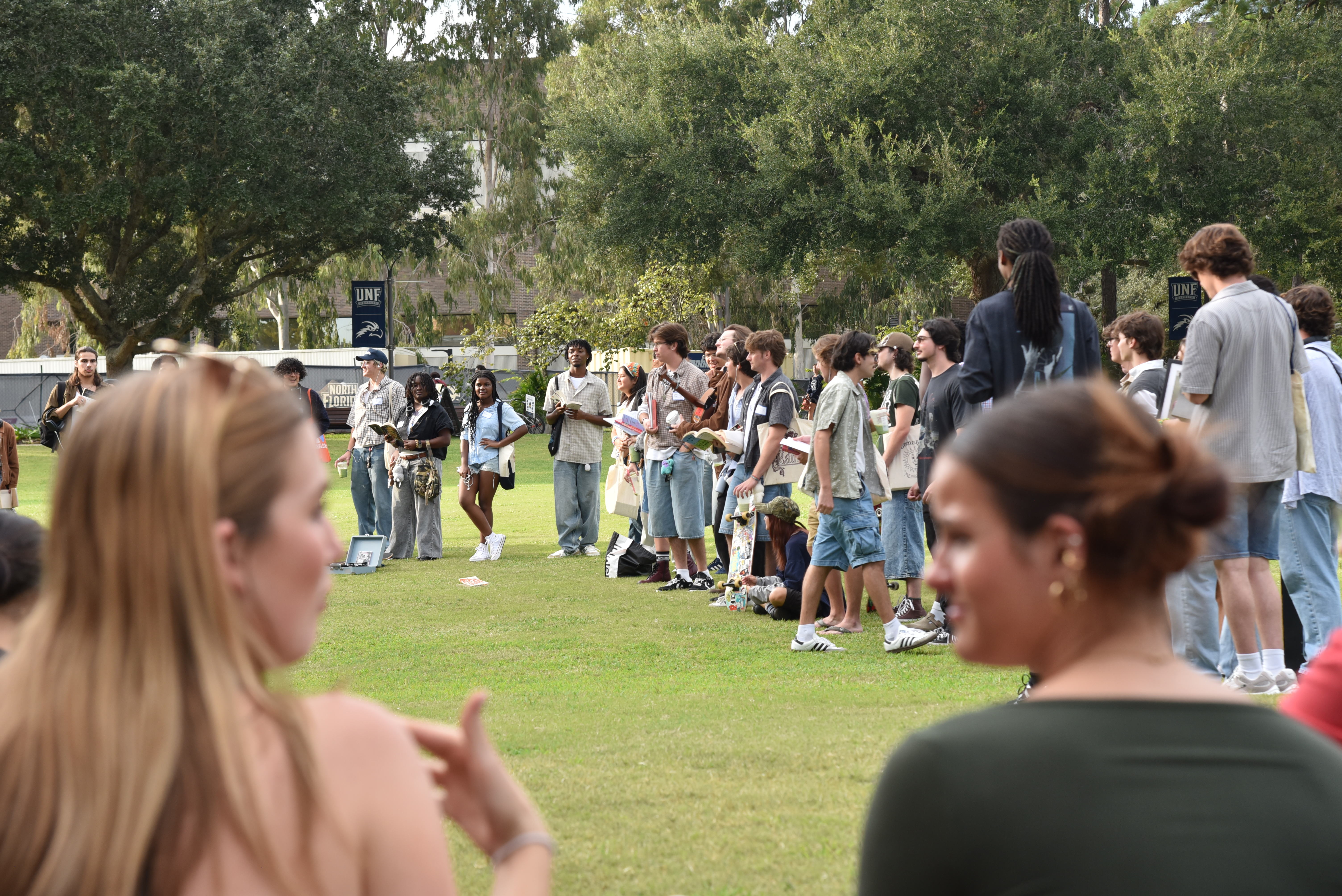Two students talk to one another while watching the contest play out from a pic nic blanket.